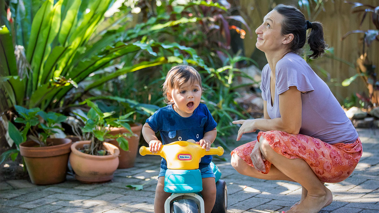 madre con niño en motoclicleta en el jardín de su casa