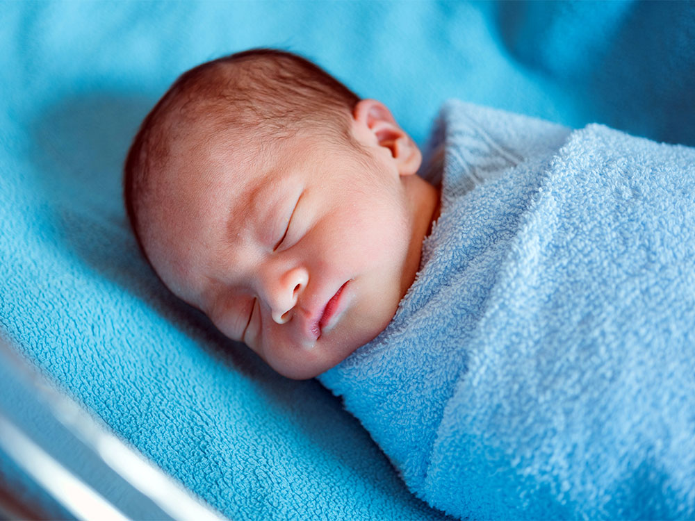 newborn baby sleeping in bed with parents